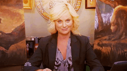 a woman sits at a desk in front of a painting that says nbc