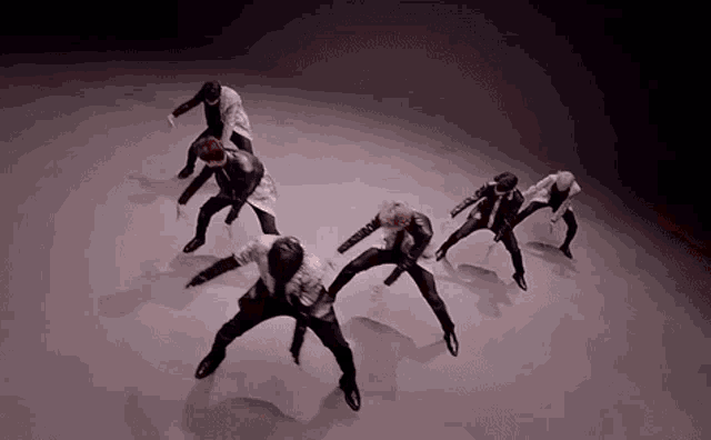 a group of men are dancing together in a dark room .