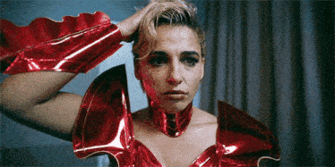 a woman is wearing a red costume and holding her hair in her hand .