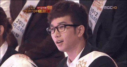 a man with glasses and a sash that says 2012 on it