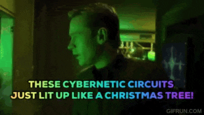 a man is standing in a dark room with a christmas tree in the background and says these cybernetic circuits just lit up