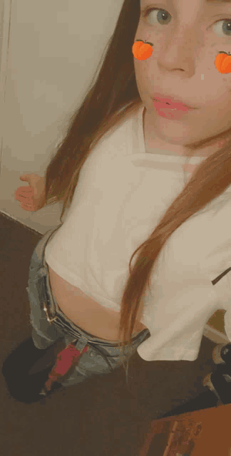 a girl with freckles on her face is wearing a white crop top and denim shorts