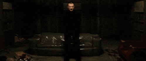 a man is standing in a dark room with a couch