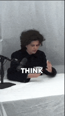 a person sitting at a desk with a microphone and the word think above them