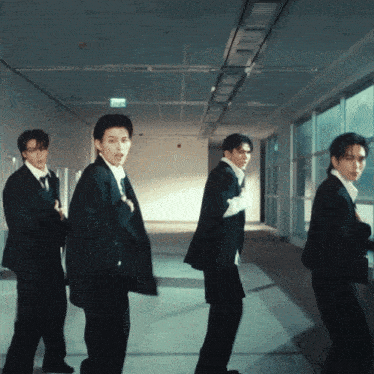 a group of men in suits are standing in a hallway