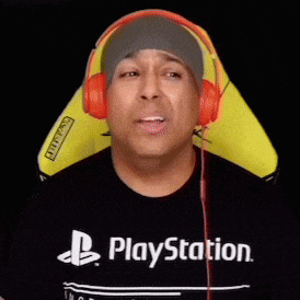 a man wearing headphones and a playstation shirt is sitting in a chair