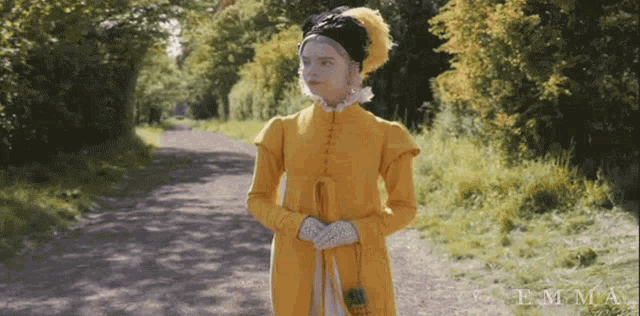 a woman in a yellow dress is standing on a path with the name emma on the bottom