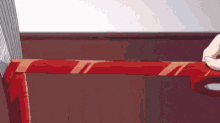 a person is cutting a piece of red tape on a wooden table .