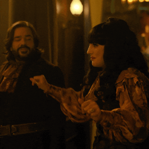 a man and a woman are standing in a dark room