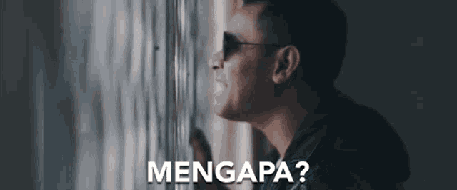 a man wearing sunglasses is looking out a window with the words mengapa written on the bottom