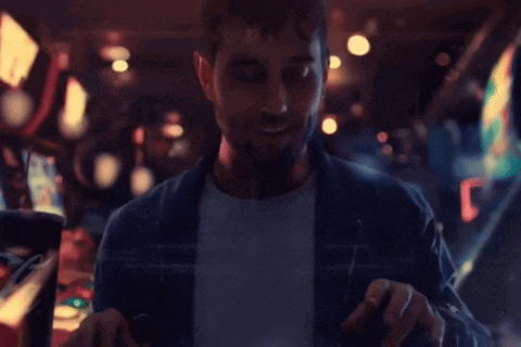 a man with a beard is playing a video game in an arcade