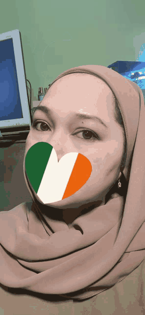 a woman wearing a hijab with an irish flag heart on her face
