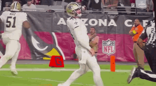 a football player is kicking the ball during a game while a referee watches .