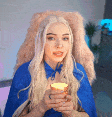 a blonde woman in a blue cape is holding a cup