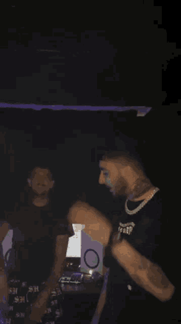 a man with a tattoo on his neck is singing into a microphone in a dark room .