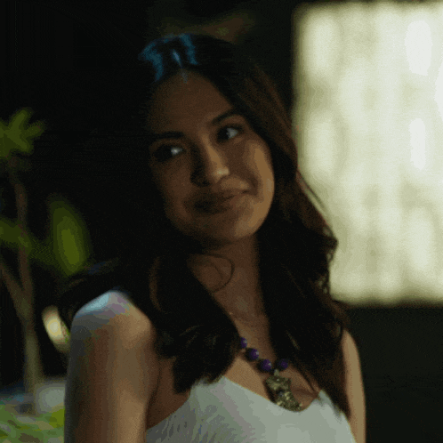 a woman wearing a necklace with purple beads is smiling