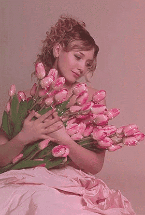 the woman is wearing a pink dress and holding a bouquet of pink flowers .
