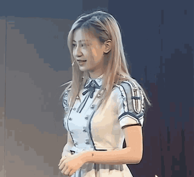 a woman in a white dress stands in front of a dark wall