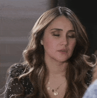 a woman with her eyes closed is wearing a necklace