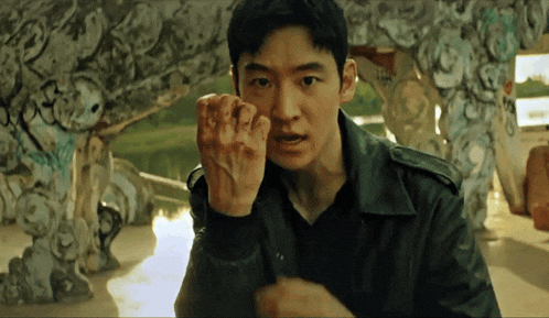 a man in a black jacket holds his fist up