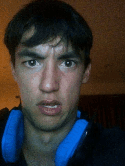 a man wearing headphones looks at the camera with a serious look on his face