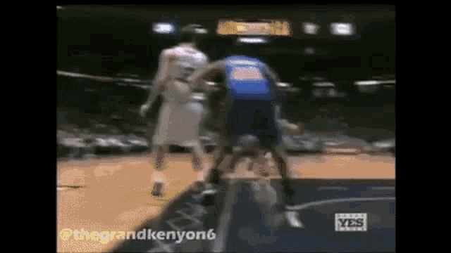 two basketball players are playing a game of basketball on a court . one of the players is wearing a blue jersey .
