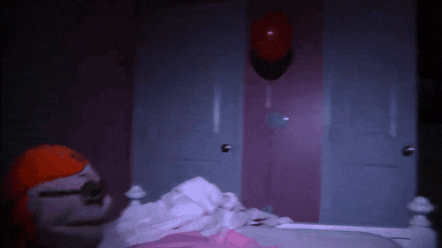 a red balloon hangs from a pink wall above a bed