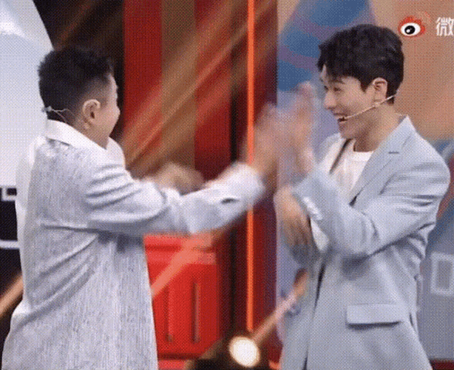 two men in suits are standing next to each other on a stage .