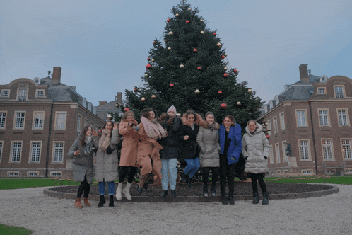 a group of women are posing in front of a christmas tree