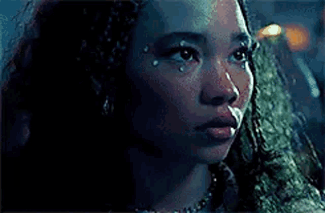 a close up of a woman 's face with a tear coming out of her eye .