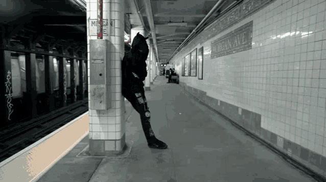 a person leaning against a pillar in a subway station with jordan ave written on the wall