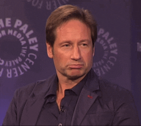 a man in a suit is making a funny face in front of a paley center logo .