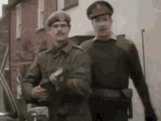 two men in military uniforms are standing next to each other .