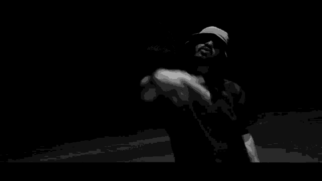 a black and white photo of a man wearing a hat and a shirt dancing .