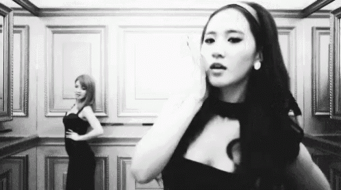 a black and white photo of two women in dresses standing next to each other in an elevator .