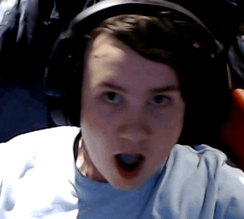a man wearing headphones and a blue shirt looks surprised