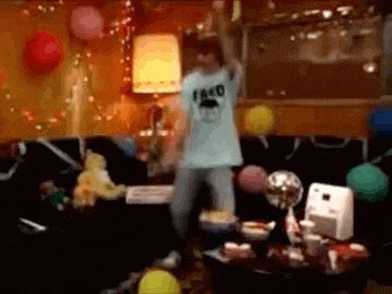a man wearing a taco shirt is dancing in a room with balloons