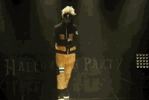 a person in a costume is walking in front of a halloween party sign