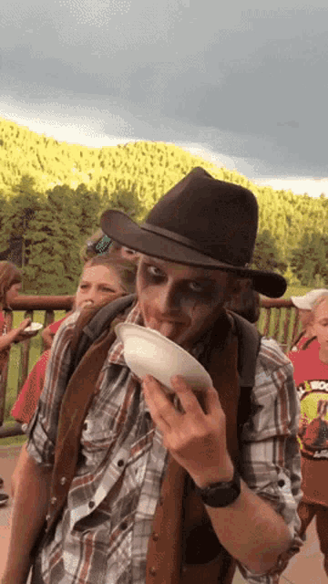 a man wearing a cowboy hat is holding a white plate