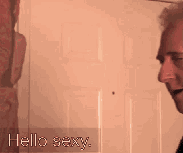 a man stands in front of a door with the words hello sexy written on the bottom