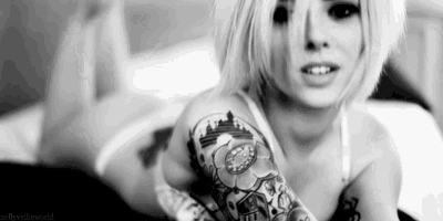a woman with a tattoo on her arm is sitting on a bed .