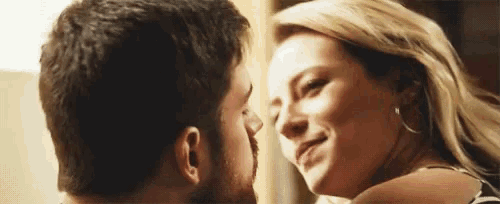 a man and a woman are kissing each other in a room .