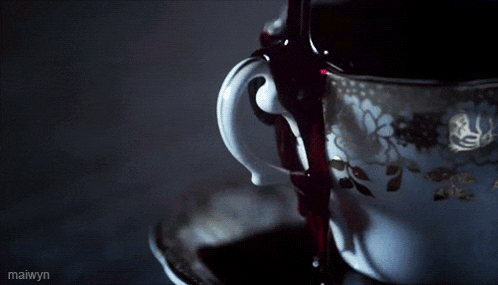 a cup of tea with a floral design is being poured