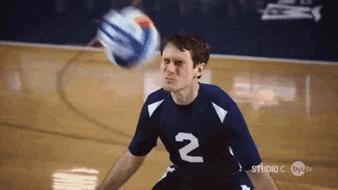 a man in a number 2 jersey is playing volleyball on a court