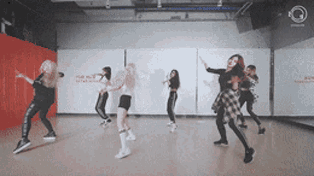 a group of young women are dancing in a dance studio with a red wall behind them that says ' dance studio ' on it