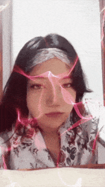 a woman in a floral shirt has a pink light behind her