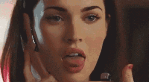 a woman is sticking her tongue out while talking on a cell phone .