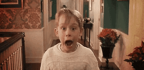 a young boy is making a surprised face in a hallway .