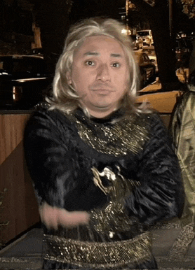 a man wearing a wig and a black and gold dress