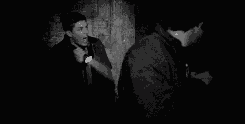 a man is holding a flashlight in a dark room in a black and white photo .